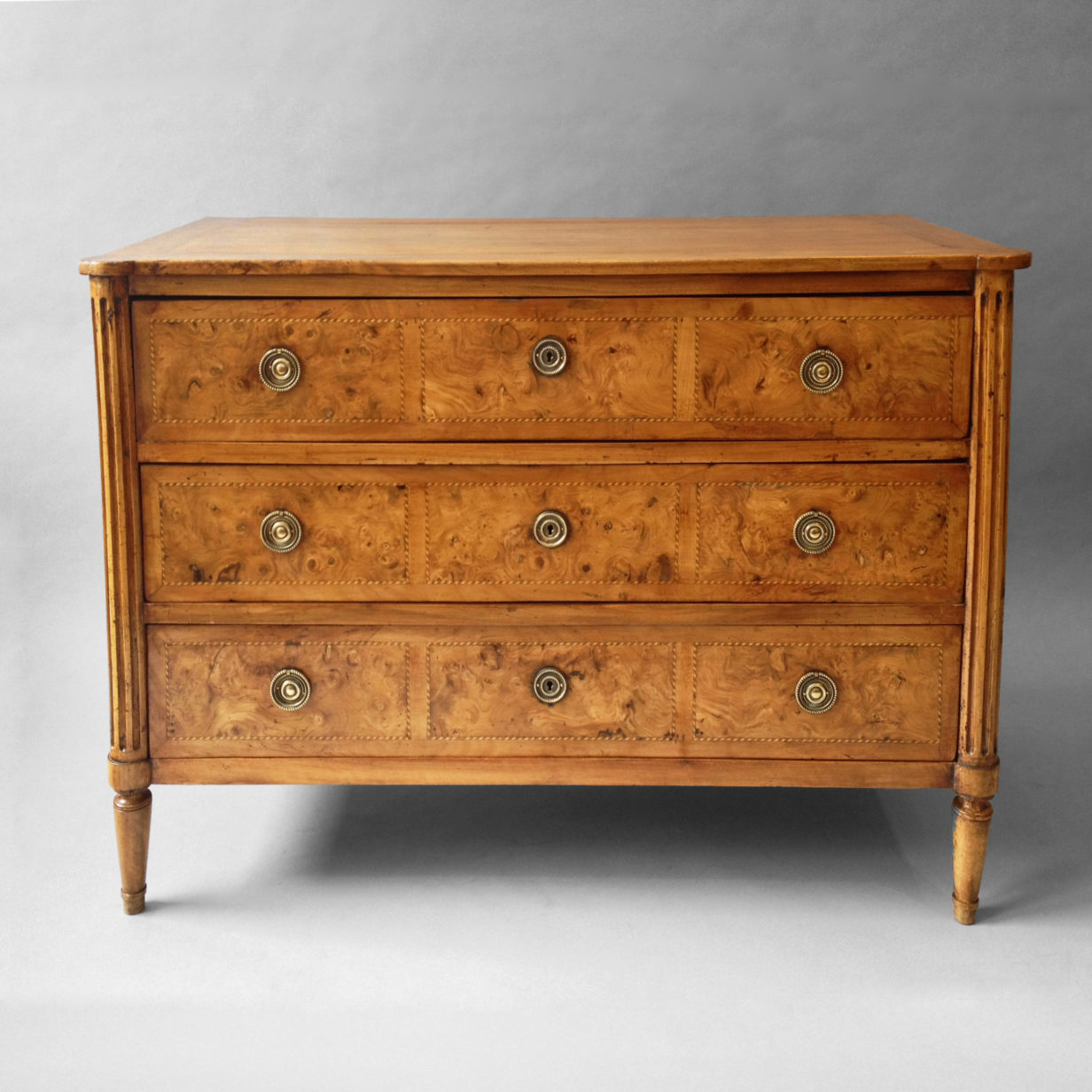 A louis xvi walnut and burr elm commode