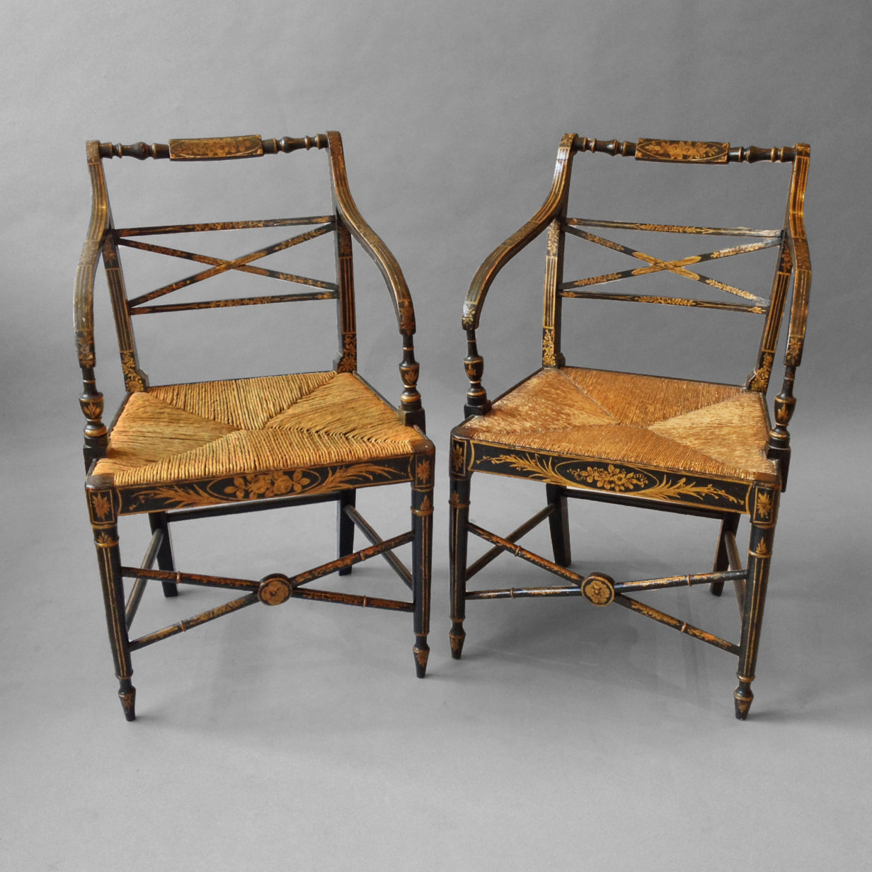 A pair of regency ebonised and gilt penwork open armchairs